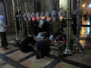 People bow down and kiss the stone where Jesus' body was supposedly laid